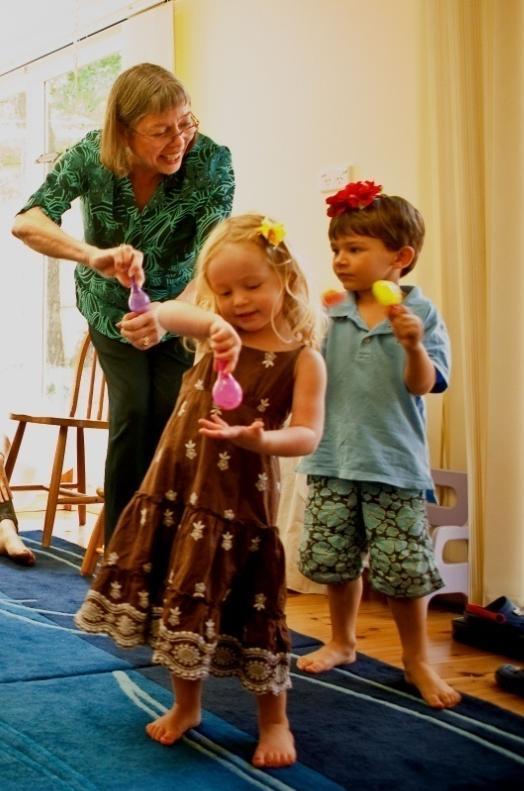 A Montessori guide and two children playing with maracas